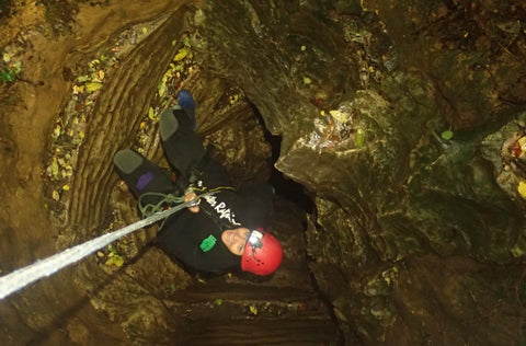 A woman is solo rappelling down into the Ruakuri cave