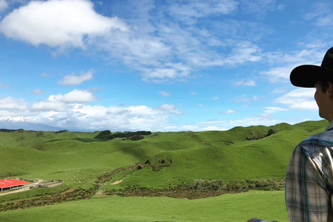 Charlie stands facing away from the camera and looking out over the hills of his sheep ranch.