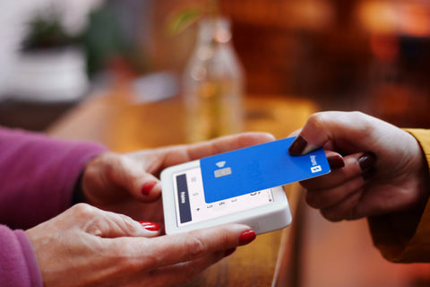 A woman completes a transaction by tapping her credit card