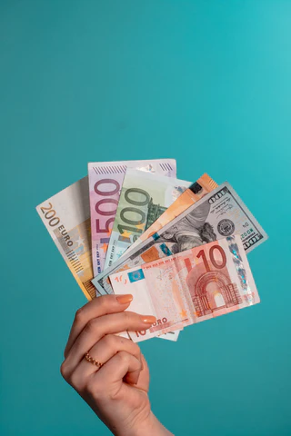 A woman's hand holding a variety of colorful foreign currencies