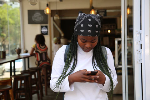 A woman looks down at her phone from an outdoor patio