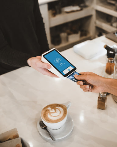 A customer at a cafe inserting her card into a credit card machine