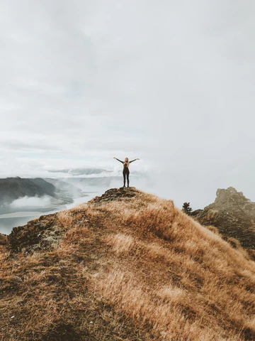 A woman standing on top of a large hill, surrounded by waterfalls