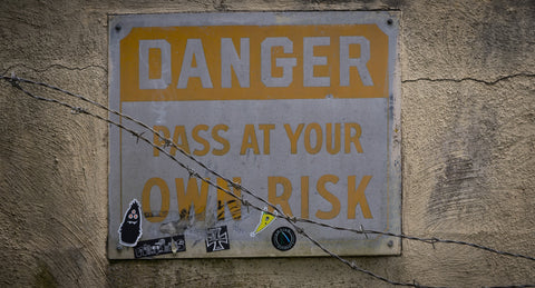 Yellow warning sign that reads "Danger pass at your own risk."