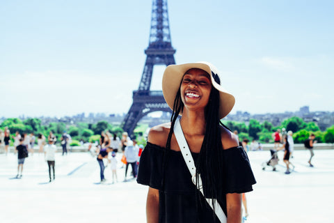 A black woman smiles at the camera with the Eiffel Tower behind her