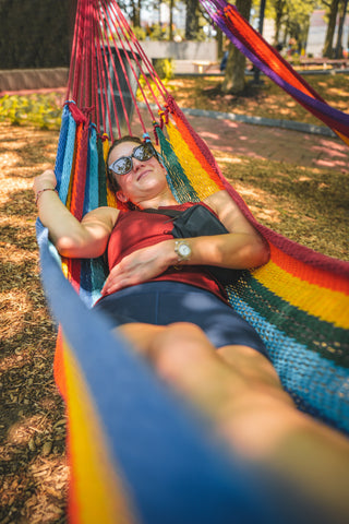 A woman lies in a colorful hammock.