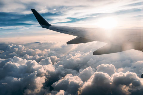 The wing tip of a plane over clouds