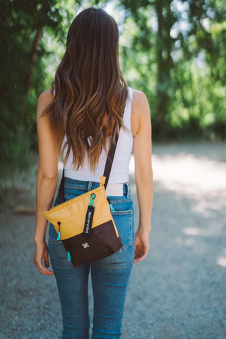 A woman walking away from the camera on a path, she is wearing Sherpani crossbody travel bag, the Sadie