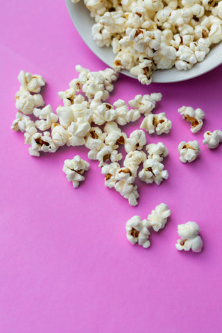 A bowl of popcorn with a pink background