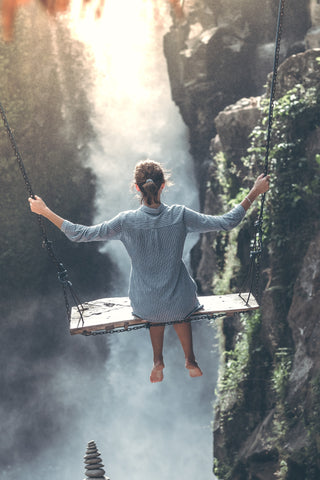 A woman on a swing overlooking a waterfall