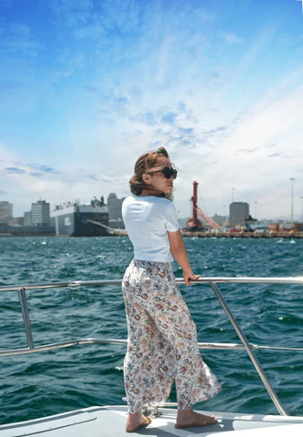 A woman standing on the bow of a sail boat