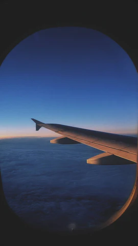 The wingtip of a plane against a darkening sky