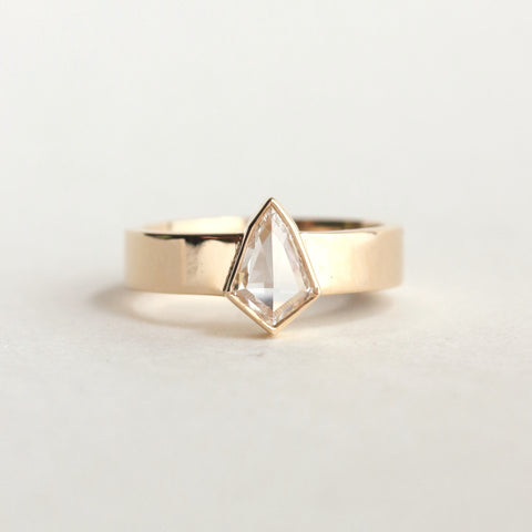 Noa features a unique, kite-cut diamond, bezel-set in a wide 14k yellow gold band. This modern kite diamond engagement ring is the answer to anyone looking for something distractingly eye-catching, and daringly unique.