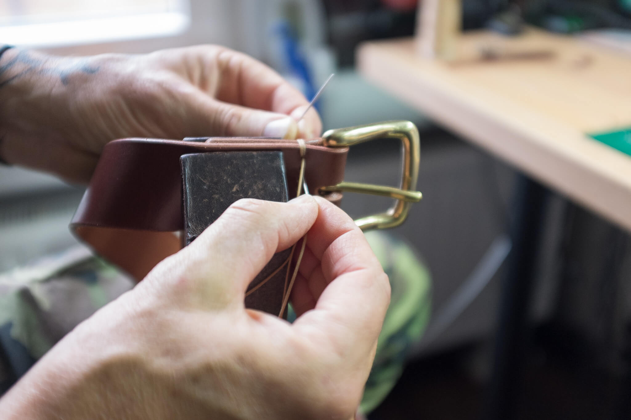 Hand stitching the belt with durable waxed thread.