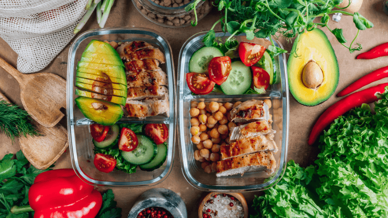 Healthy meal prep containers with chickpeas, chicken, tomatoes, cucumbers and avocados. Healthy lunch in glass containers on beige rustic background. Zero waste concept. Selective focus.