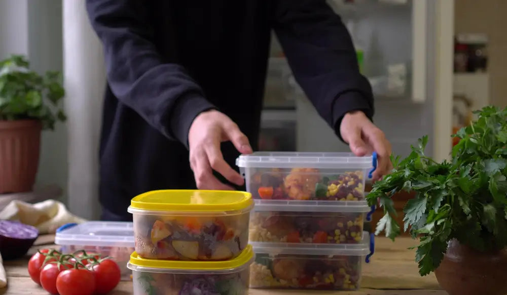 meal prep containers with food being stacked and prepared for storage
