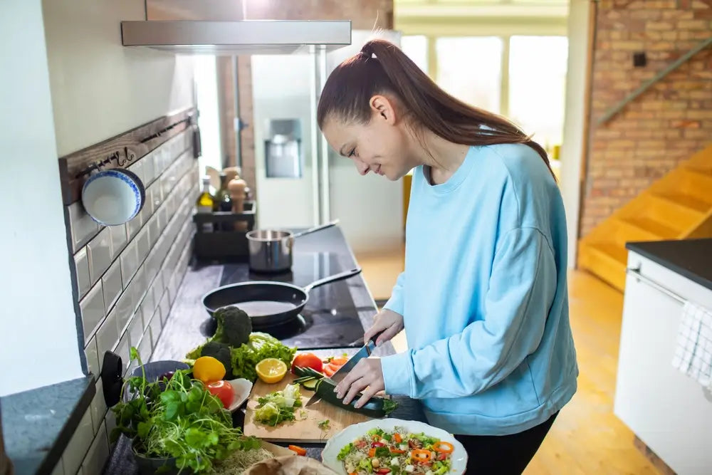 Young adult woman preparing a healthy meal in the kitchen