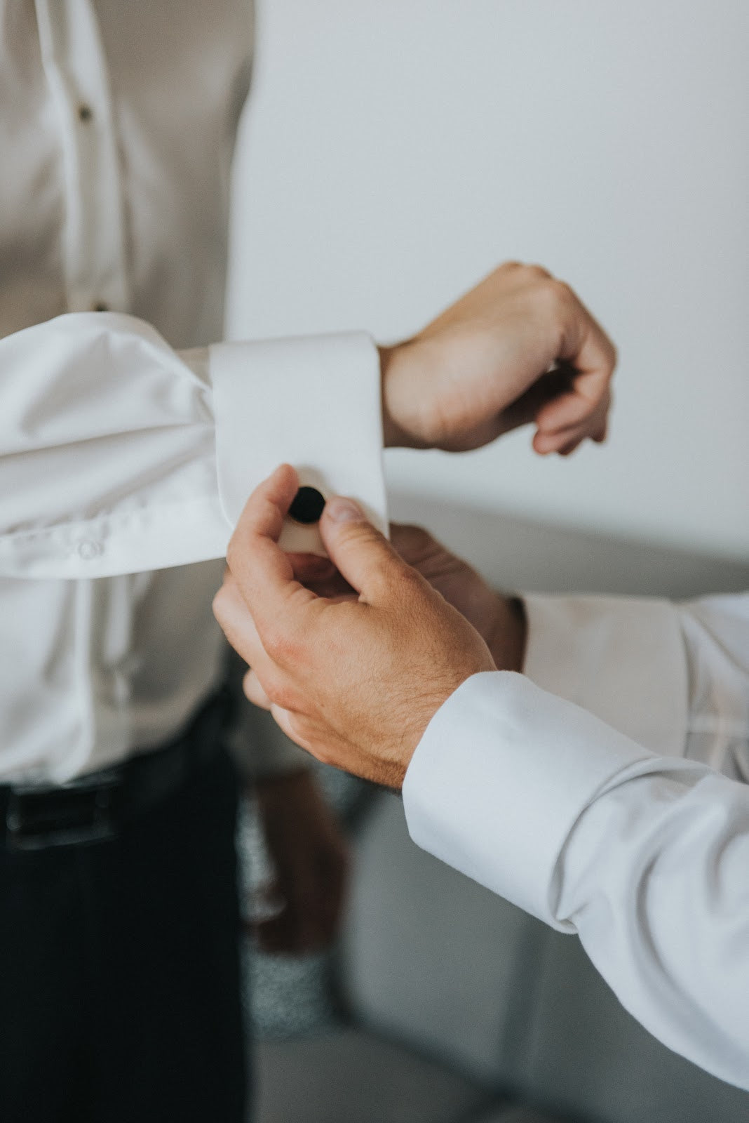 Man's hands in white shirt helping to adjust cufflink on another man in white tuxedo shirt | Style Standard