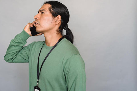 Man in long sleeved green t-shirt with ponytail talking on cell phone | Style Standard