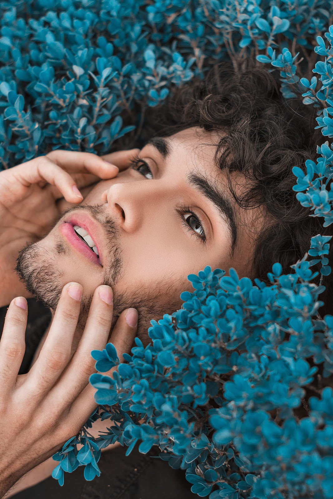 Man Touching Face Surrounded by Blue Foliage | Style Standard