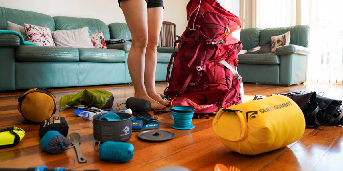 Person is organizing backpacking gear around their pack