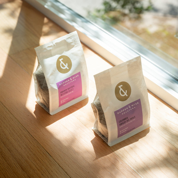 Two coffee bags on a counter by a window in a diagonal perspective