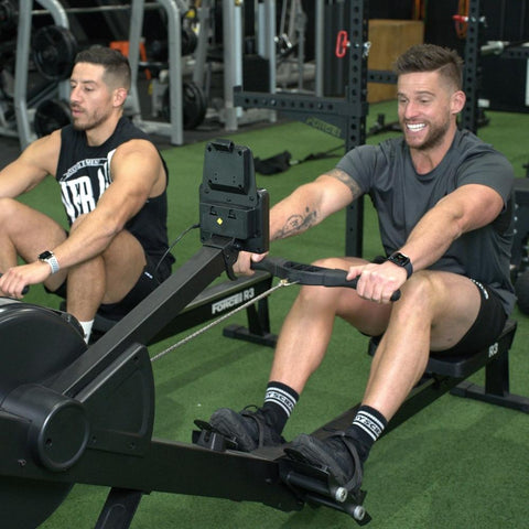 Two Males Using The Force USA Rowing Machines