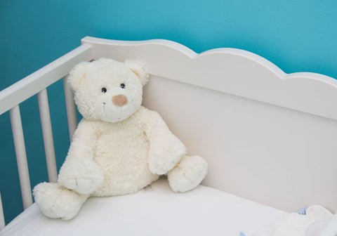 teddy bear in crib in blue room