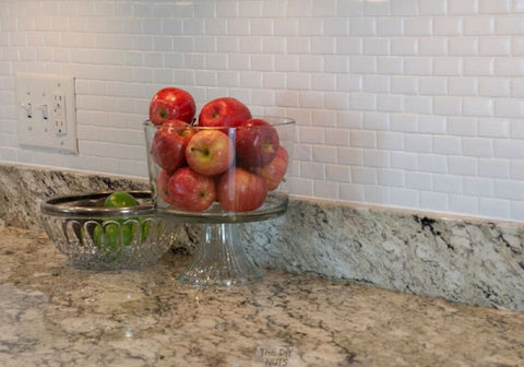 white kitchen backsplash with glass container of apples