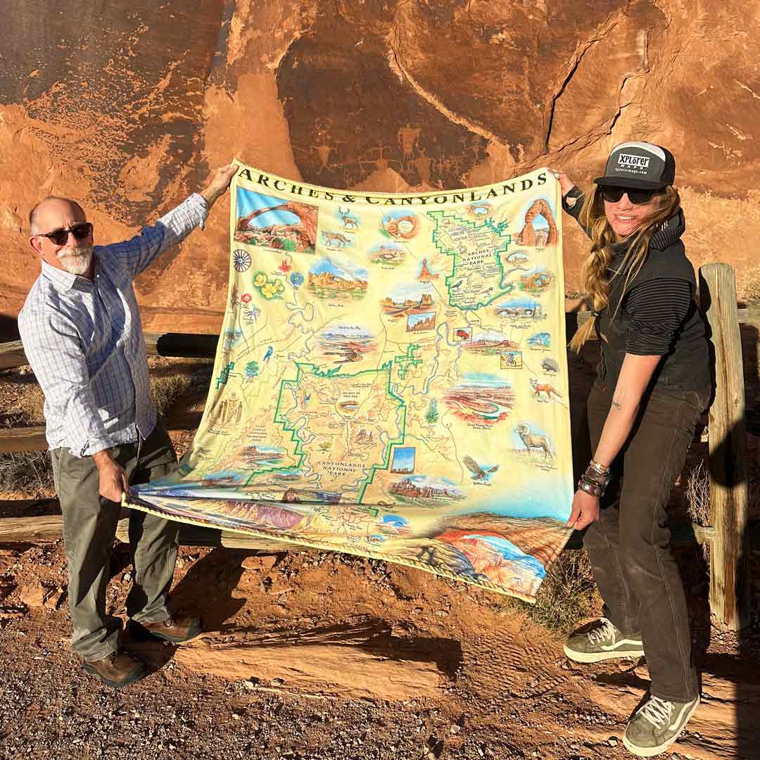 Mandela and Sam holding Arches and Canyonlands blanket. In the background is Arches National Park.