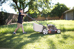 Younger child mowing the lawn using push lawnmower