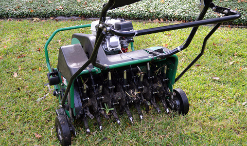 core aerator removing plugs from lawn soil