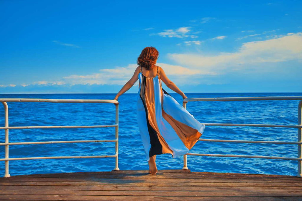 lady wearing a flowing dress and looking into the blue ocean