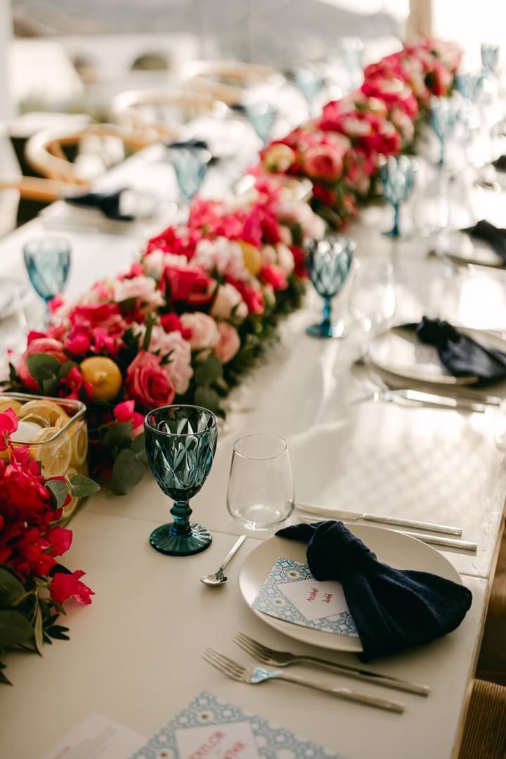 Greece inspired wedding menus on a dining table with pink flowers in Ios, Greece