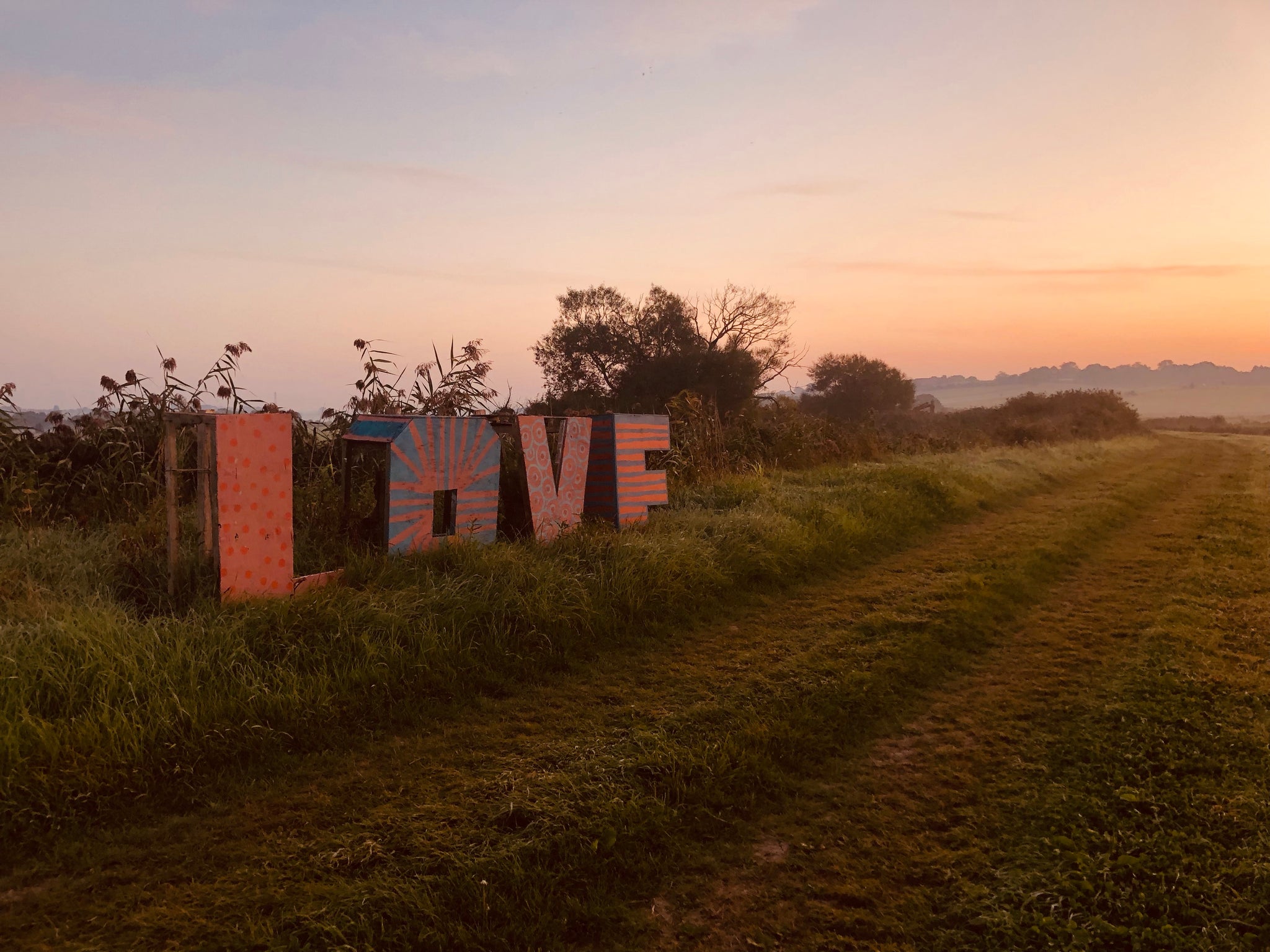 A painted sign saying LOVE photographed at sunrise