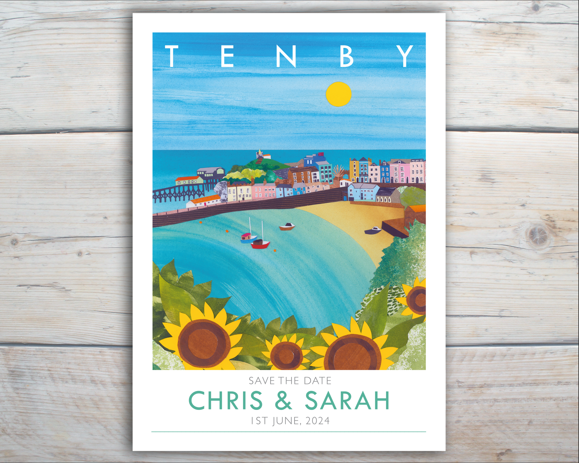 An illustrated wedding invitations featuring a bright collage of Tenby, Wales lays on a grey wooden background