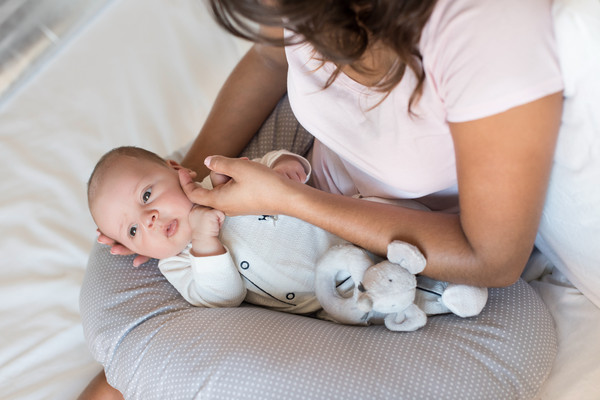 closeup image of a young woman holding here newborn baby on a nursing pillow