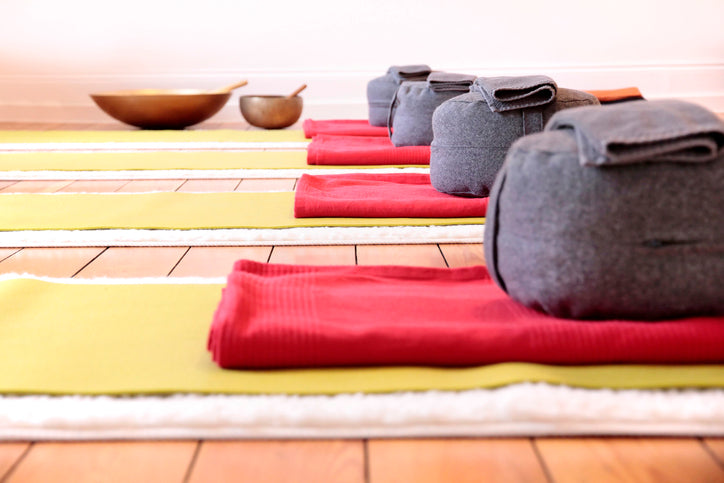 several meditation cushions lined up in a yoga studio