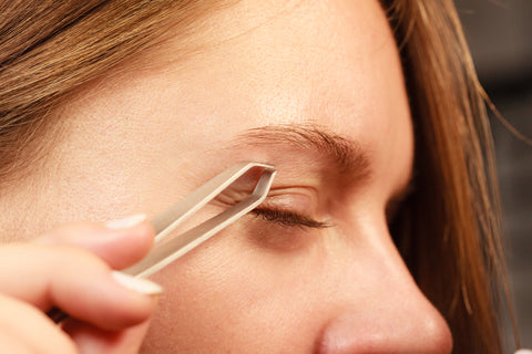 Woman-plucking-eyebrows-with-tweezer