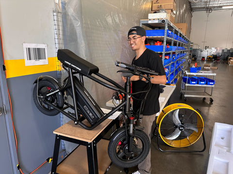 VoroMotors technician performing the first quality check in the Kapolei location on an EMOVE RoadRunner electric scooter, scooter is propped on table with Micah behind