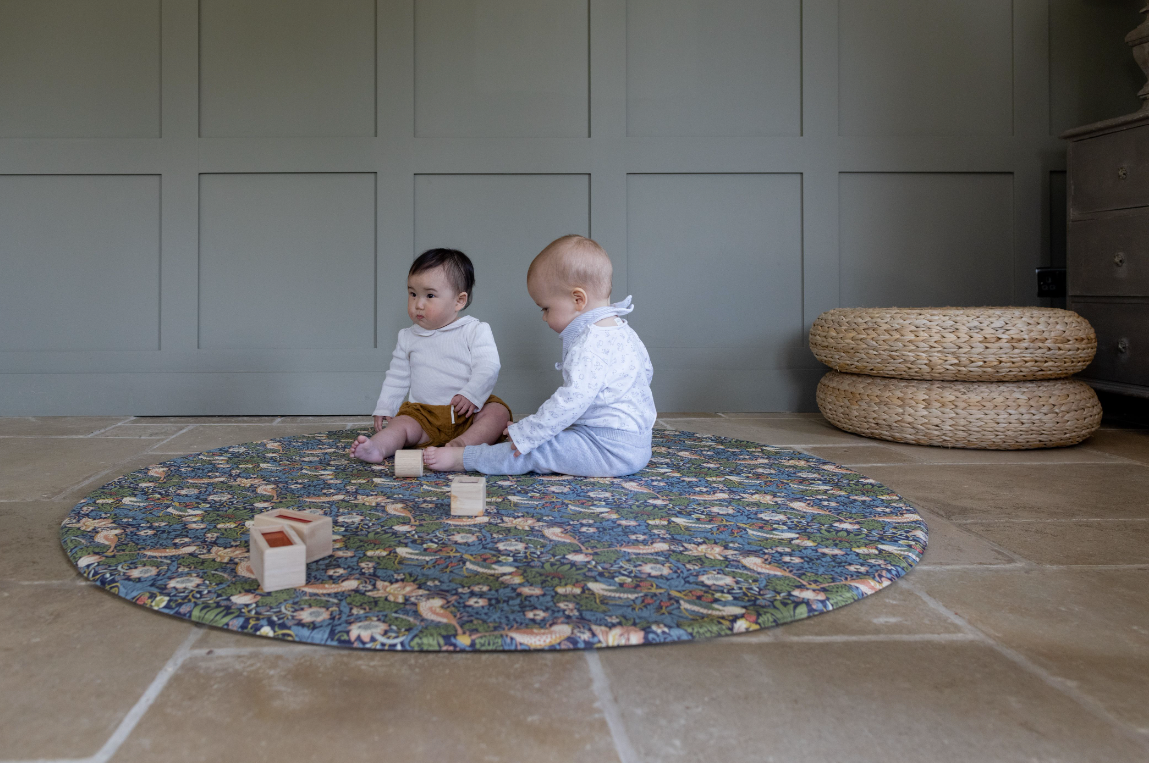 babies playing on round Strawberry Thief playmat