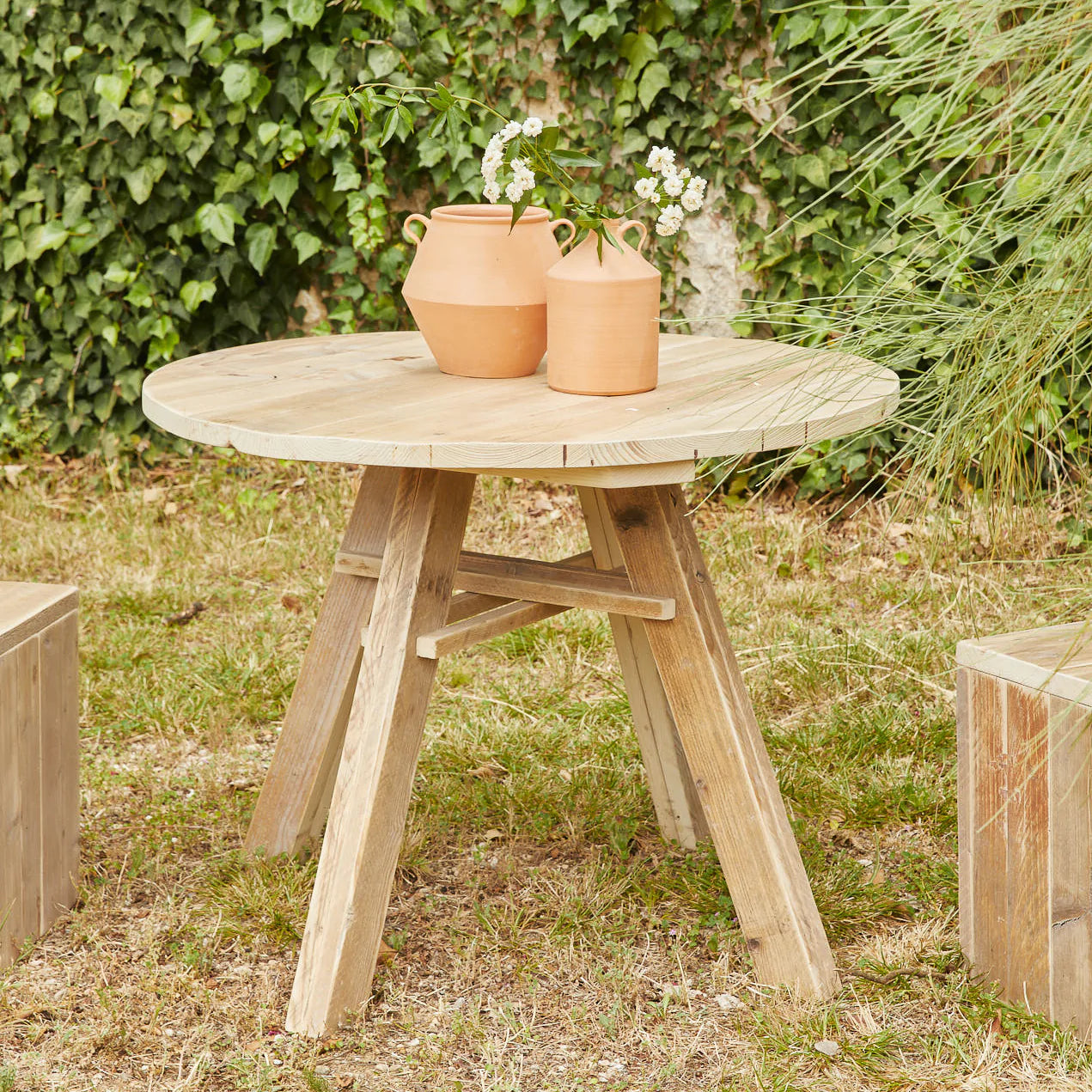 Mesa de exterior redonda fabricada artesanalmente con madera recuperada de abeto nórdico.