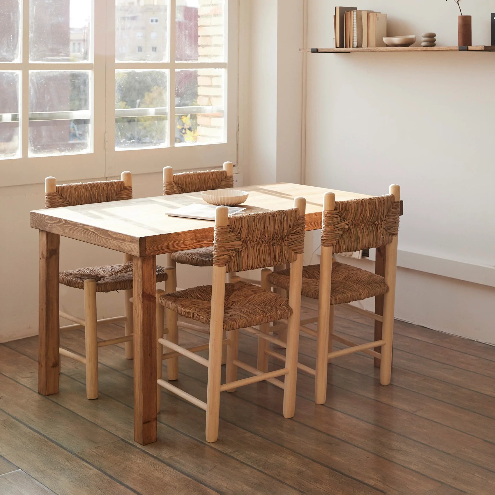Mesa de comedor de madera recuperada y sillas de fibras naturales.