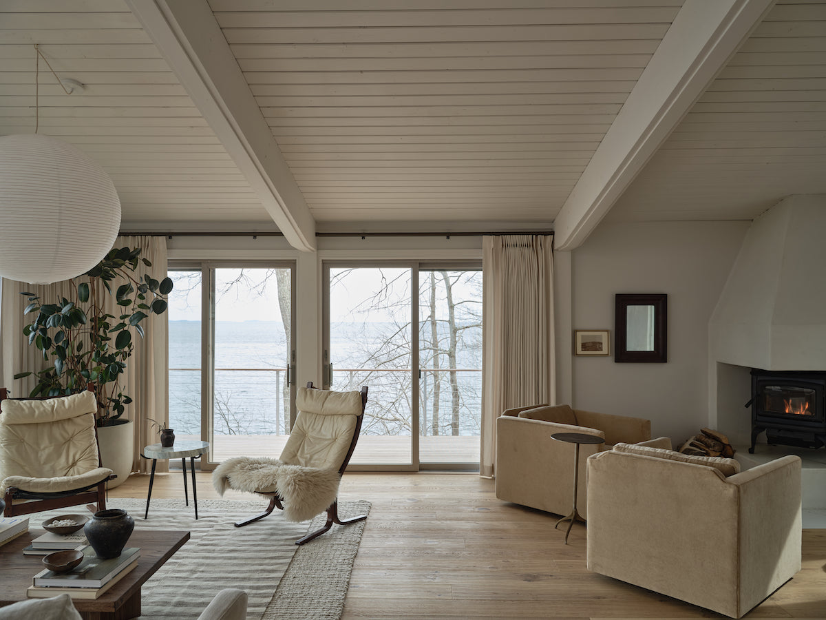A midcentury modern living room with warm white oak flooring in dim sunlight