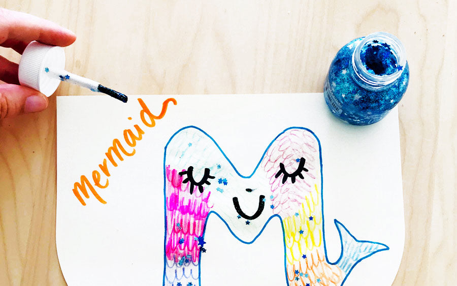 Adding Pixie Paste glitter glue on mermaid letter art for kids