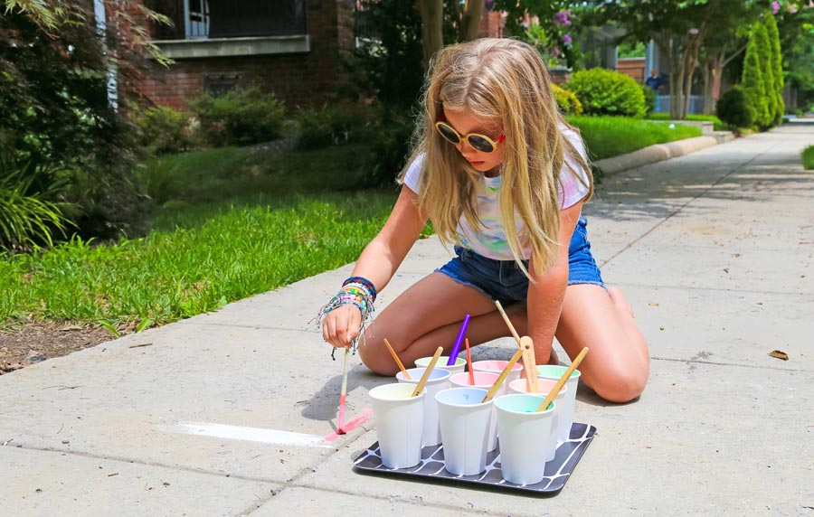 Girl painting on sidewalk with homemade sidewalk chalk paints 