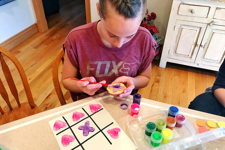 Kid painting potato stamp with OOLY poster paints to make tic-tac-toe