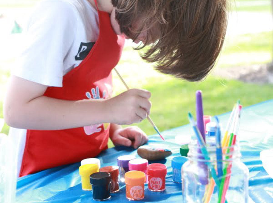 Kid painting rock with poster paints