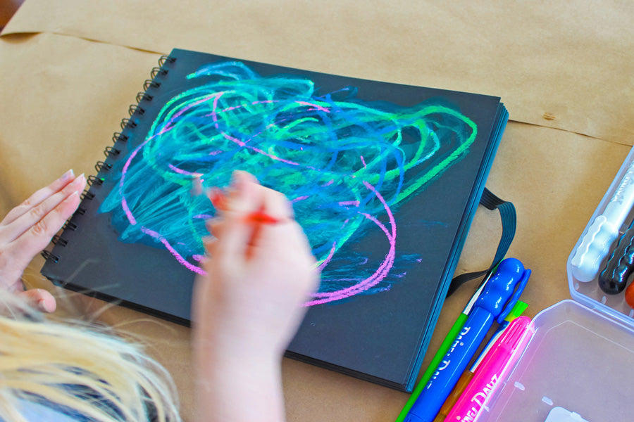 Cam scribbling colors across her "sky" and blending them with water and a brush for a hazy watercolor effect.