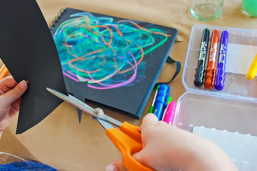 Cutting out an outline of mountains from a separate sheet of black paper.